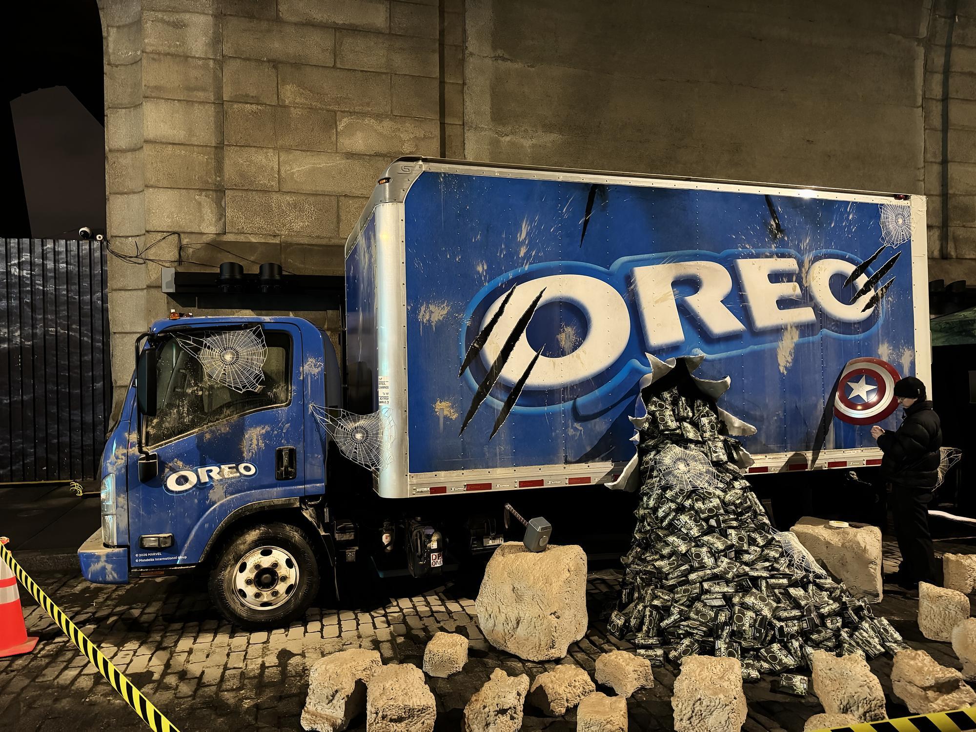 Night installation: a wrapped box truck with claw marks and a burst of product spilling onto cobblestones